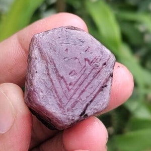 May include: A purple gemstone with a faceted cut and a star-like pattern on the surface.