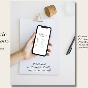 May include: A smartphone displaying an electronic invitation for a "Saturday mimosa brunch" with a graphic of a mimosa glass. The text on the screen reads "Saturday mimosa brunch" and includes the date, time, and location of the event. The phone is held in a hand, and the background is a white surface with a pen and a cork.