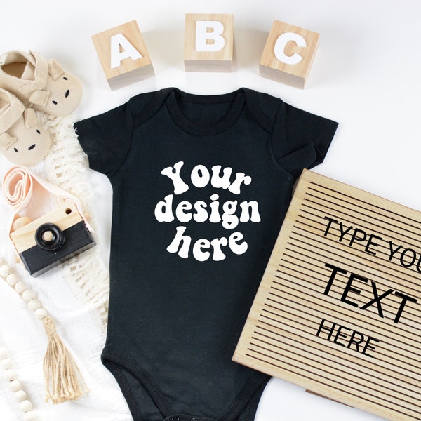 Baby bodysuit mockup with letter board Flat lay short sleeve body suit mock up baby flatlay mock-up with wooden camera