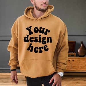 Könnte beinhalten: Ein senfgelber Hoodie mit einem schwarzen Aufdruck, der "Your design here" lautet.