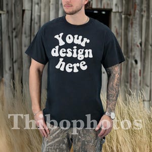 May include: A black t-shirt with the text "Your design here" in white lettering. The shirt is being worn by a person standing in front of a wooden fence.