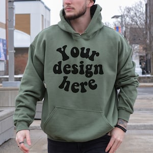 Op de afbeelding: Een groen hoodie met de tekst "Your design here" in zwarte retro-letters.