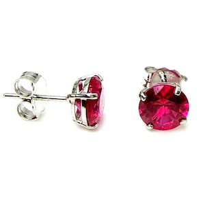 May include: A pair of silver stud earrings with a bright red round gemstone in each earring.