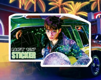 May include: A sticker featuring a young man with purple hair wearing a blue denim jacket and sunglasses, leaning out of a green car. The sticker has the text "NCT 127 STICKER" in green letters.