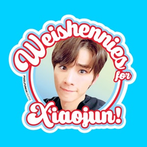 May include: A red and white sticker with the text "Weishennies for Xiaojun!" in a retro font. The sticker features a photo of a young man with dark hair and a light blue background.