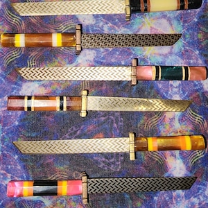 May include: Six miniature swords with patterned blades and colorful handles, displayed on a purple and blue patterned fabric with a brown leather sheath.