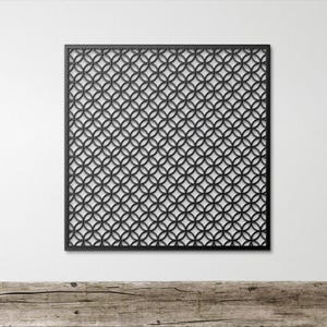 May include: Black metal wall art featuring a repeating pattern of interlocking circles. The square panel is mounted on a white wall, with a wooden surface in the foreground. The design creates a geometric, modern aesthetic.