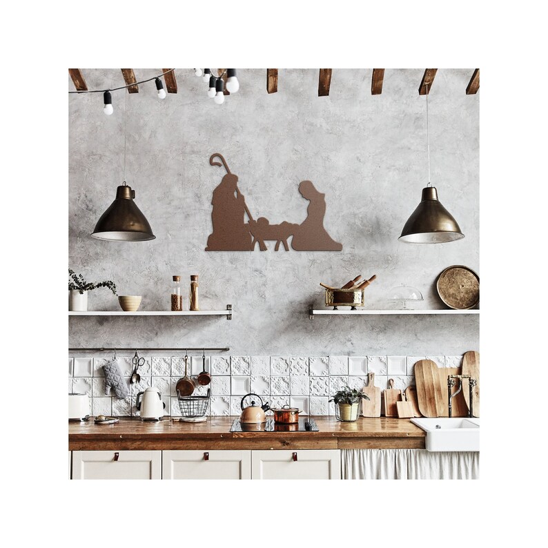 May include: A brown metal silhouette of the nativity scene with Mary, Joseph, and baby Jesus in a manger. The silhouette is mounted on a grey wall in a kitchen setting with white tiled backsplash and wooden worktops.