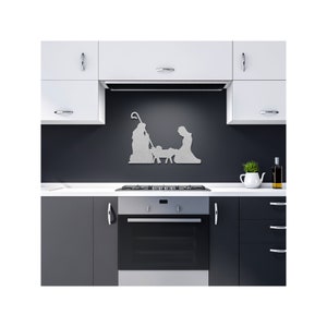 May include: A metal silhouette of the nativity scene, featuring Mary, Joseph, and the baby Jesus, with a sheep, is displayed on a black kitchen backsplash.