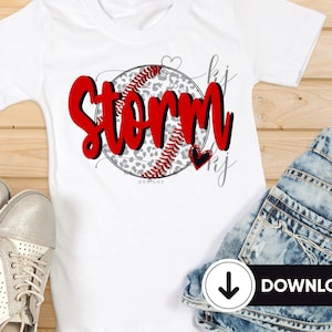 May include: White t-shirt with a red and black baseball graphic with a leopard print design. The word "Storm" is written in red with a black outline. Two small hearts are on either side of the baseball.