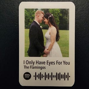May include: A wedding photo of a couple in a green field with the song "I Only Have Eyes For You" by The Flamingos and a Spotify barcode.