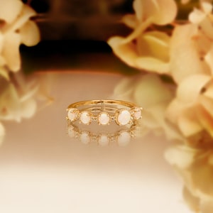 May include: A gold ring with five white oval stones set in a delicate band.
