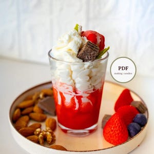 May include: A candle shaped like a layered dessert in a clear glass. The candle has a red base, white whipped cream, and is topped with a red cherry, chocolate wafer, and mint. The candle sits on a plate with almonds, chocolate, and strawberries. The text "PDF making candles" is in a circle.