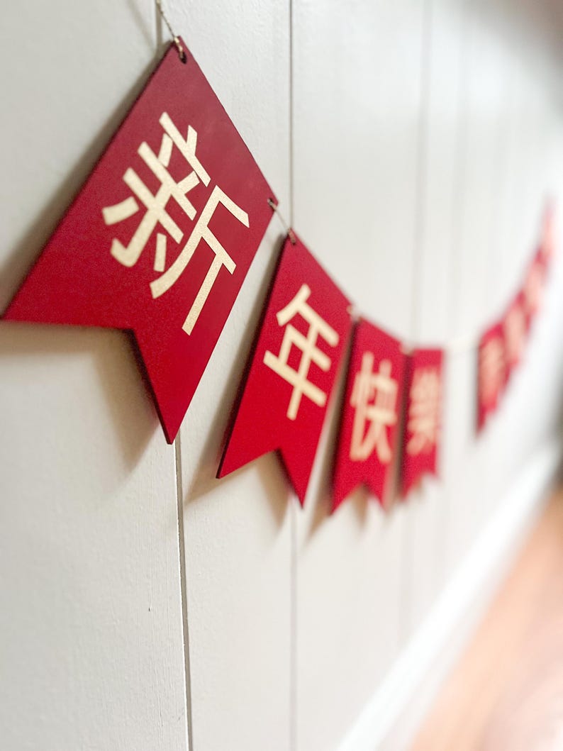 May include: Red and gold Chinese New Year banner with the characters "新年快乐" which translates to "Happy New Year".