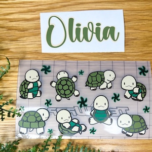 Peut inclure: Une feuille de vinyle transparent avec une grille et neuf autocollants de tortues vertes et blanches. Les autocollants présentent différentes poses de tortues et portent le nom "Olivia" écrit sur un autocollant séparé.