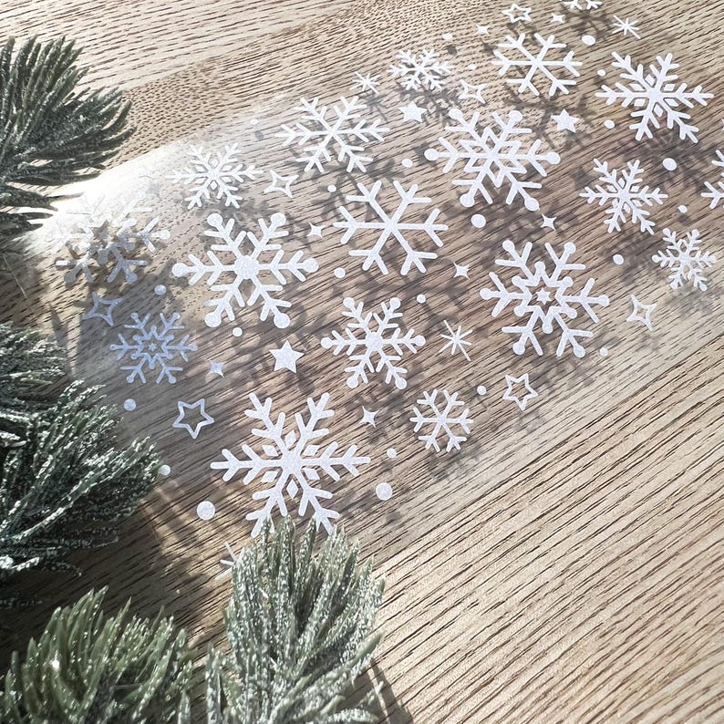 May include: A sheet of clear adhesive paper with white snowflake stickers. The snowflakes are various sizes and shapes.