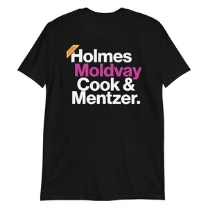 Op de afbeelding: Zwart T-shirt met witte tekst die "Holmes Moldvay Cook & Mentzer." luidt.