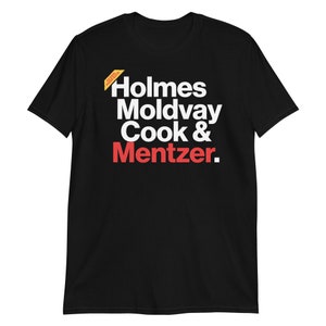 May include: Black t-shirt with white text that reads "Holmes Moldvay Cook & Mentzer." The word "Mentzer" is in red. A small yellow and white tag is in the upper left corner of the shirt.