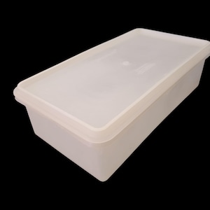 May include: A rectangular, off-white plastic container with a matching lid. The container has a simple, clean design, with slightly rounded edges and a smooth surface. The lid fits snugly on top, creating a secure seal. The container is likely used for food storage.