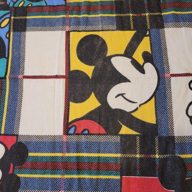 Peut inclure: Tissu &agrave; motif &eacute;cossais avec Mickey Mouse. Les carr&eacute;s ont un fond jaune avec le visage et le corps de Mickey Mouse. Le motif &eacute;cossais comprend des rayures bleues, rouges, vertes et noires, avec des carr&eacute;s blancs.
