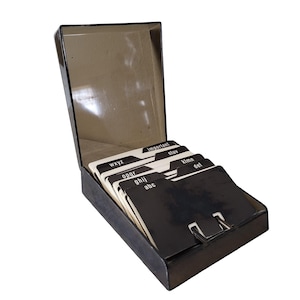 Peut inclure: Un classeur d'adresses noir vintage avec un couvercle à charnière, contenant un ensemble de fiches alphabétiques. Les cartes sont noires avec des lettres blanches, et les onglets sont étiquetés avec des lettres et le mot "important".