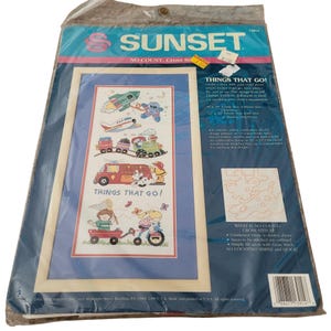 Puede incluir: Un kit de punto de cruz Sunset No Count titulado Things That Go, con un diseño impreso en tela de un cohete, avión, tren, camión de bomberos y niños con un carrito y bicicleta. El empaque incluye instrucciones y especifica un tamaño de marco de 20cm por 45cm.