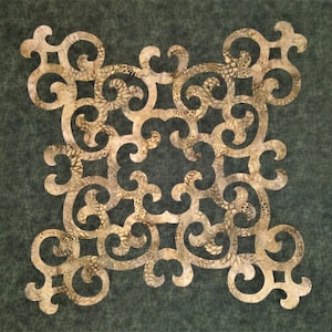 May include: A gold-colored, intricate, decorative design with a swirling pattern. The design is cut out of fabric and has a dark green background.