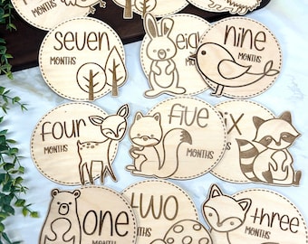 May include: Wooden baby milestone discs with a woodland theme. Each disc features a different animal and number, from one to ten, with the words "months" or "year" printed on each disc.
