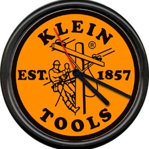 May include: A black and orange round wall clock with the Klein Tools logo. The logo features a lineman working on a utility pole with the text "Klein Tools" and "Est. 1857".