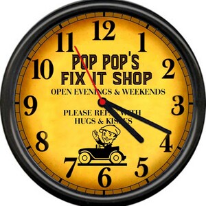 May include: A black and yellow clock with the text "Pop Pop's Fix It Shop" and "Open Evenings & Weekends". The clock also has the text "Please Repair With Hugs & Kisses" and a cartoon image of a man driving a car.