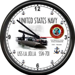 May include: A black and white clock with a white face. The clock face features a submarine, the words "United States Navy", "USS La Jolla SSN-701", and "Los Angeles-class Attack Submarine 1981 - Present".