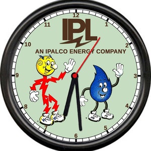 May include: A black framed clock with a green face. The clock features the IPL logo, the text "AN IPALCO ENERGY COMPANY", and two cartoon characters. One character is a blue water drop with a smiling face and the other is a red lightning bolt with a smiling face.
