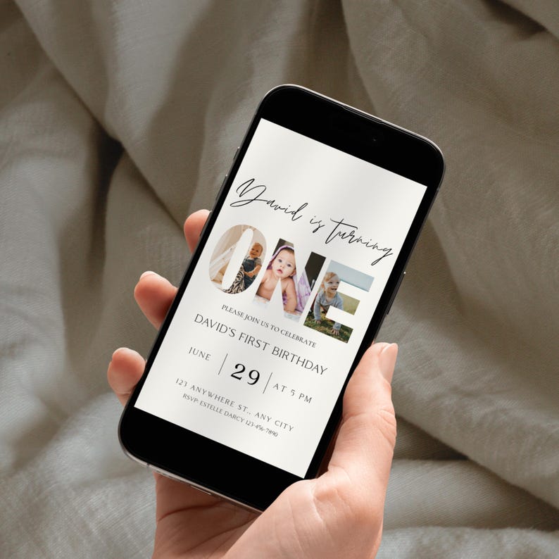May include: A smartphone displays a digital invitation for a first birthday. The invitation features the text "David is turning ONE" with photos, date, time, and RSVP details. The phone is held against a neutral background.