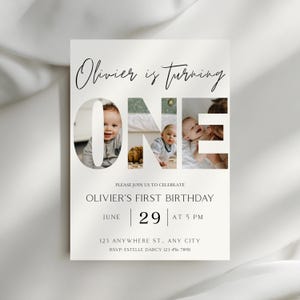 May include: A cream-colored invitation card with the text "Olivier is turning ONE." The word "ONE" features photos of a baby. The card also includes the text "Olivier's First Birthday" and event details.