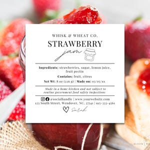 Op de afbeelding: Een pot aardbeienjam met een wit etiket. Het etiket luidt "WHISK & WHEAT CO. STRAWBERRY jam" en vermeldt ingrediënten en nettogewicht van 226 g. Verse aardbeien en een sneetje toast met jam op de achtergrond.