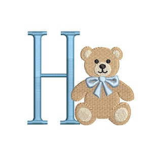 May include: A light blue embroidered letter "H" next to a tan teddy bear with a light blue bow. The teddy bear has black eyes and a black nose. The design is on a white background.