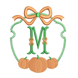 Puede incluir: Diseño bordado con la letra "M" verde y detalles en naranja. La letra está rodeada por un borde verde cosido, un lazo naranja y tres calabazas naranjas. Ideal para manualidades con temática otoñal.