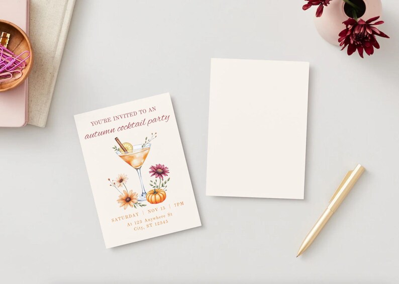 May include: An invitation card for an autumn cocktail party. The card features a watercolor illustration of a cocktail, flowers, and a pumpkin. The text reads "You're invited to an autumn cocktail party". A blank card and a gold pen are also present.