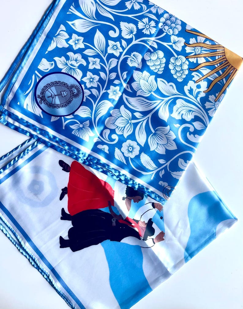 May include: Two square silk scarves. One features a blue and white floral pattern with a circular emblem and a sun design. The other scarf has a white background with a blue wave design and a graphic of two people dancing in red and black.