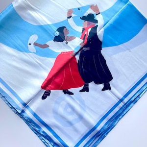 May include: Square white scarf with a blue and white design featuring a couple dancing. The woman wears a red skirt and white top, while the man wears black pants and a hat. The scarf has a blue border.