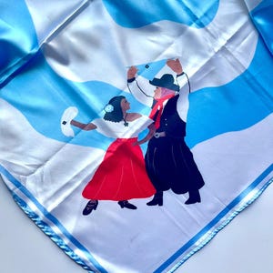 May include: Square silk scarf with a blue and white abstract pattern and a depiction of two people dancing. The dancers are wearing traditional clothing, with a red skirt and black skirt. The scarf has a blue border.