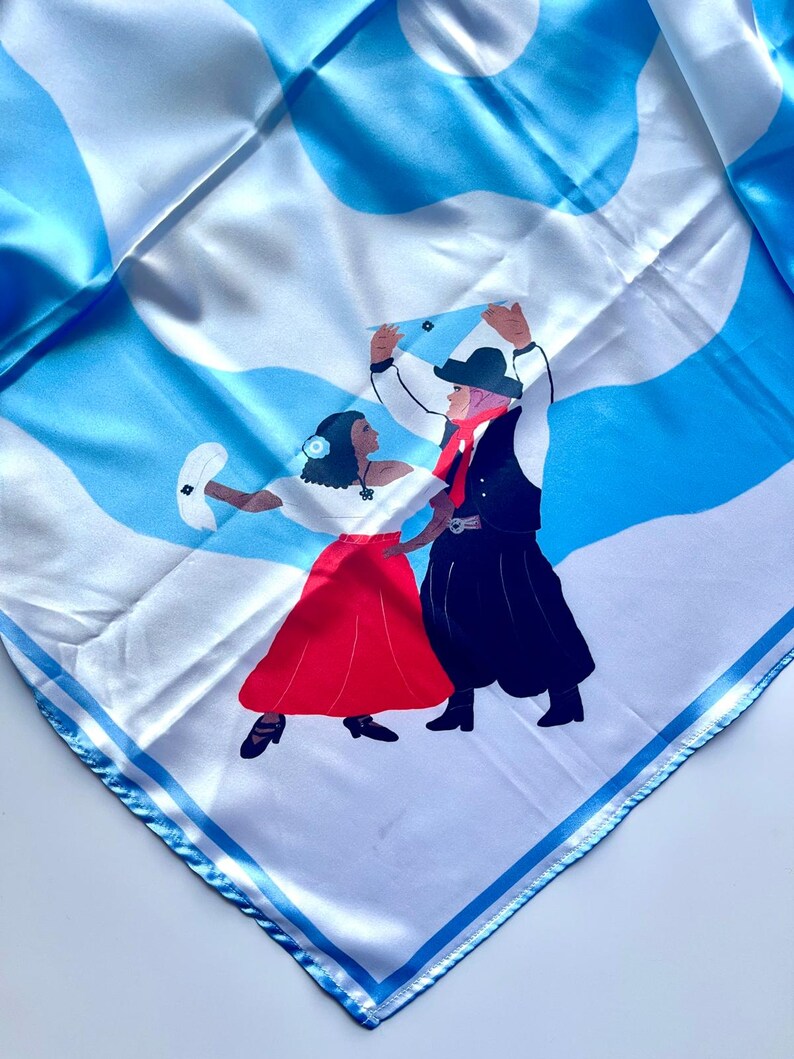 May include: Square silk scarf with a blue and white abstract pattern and a depiction of two people dancing. The dancers are wearing traditional clothing, with a red skirt and black skirt. The scarf has a blue border.
