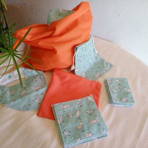 May include: A collection of handmade items: an orange tote bag, a matching zipped pouch, a bib, a drawstring bag, and several square cloths. The cloths and bags feature a light teal fabric with a repeating bird pattern.