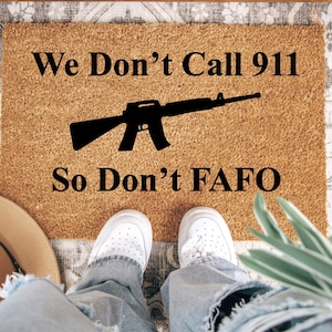 May include: A brown doormat with the text "We Don't Call 911 So Don't FAFO" and a black silhouette of a rifle.