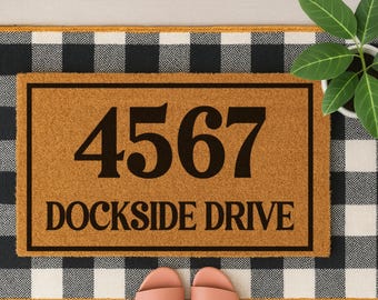 May include: A brown coir doormat with black text that reads "4567 Dockside Drive" on a black and white checkered background.