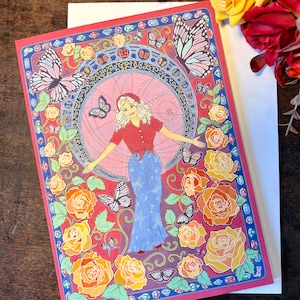 Peut inclure: Une carte de vœux avec une illustration colorée. La carte représente une femme en chemise rouge et pantalon bleu, entourée de papillons et de roses. Le fond est rose et le bord est rouge et bleu.