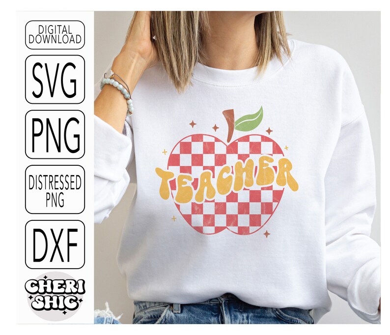 May include: White sweatshirt with a red and white checkered apple design and the word "TEACHER" in yellow letters.