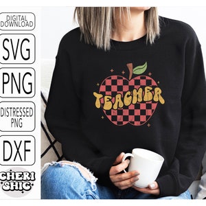 May include: A black sweatshirt with a red and black checkered apple design and the word "TEACHER" in a retro font.