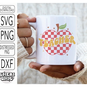 May include: White ceramic mug with a red and white checkered apple design. The apple has a green stem and leaves. The word "TEACHER" is written in yellow letters on the apple.
