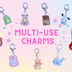 May include: A selection of multi-use charms with adorable designs, such as a frog, bear, chocolate bar, bunny, and whale. Each charm has a silver-coloured clasp. The text "MULTI-USE CHARMS" is displayed in pink.